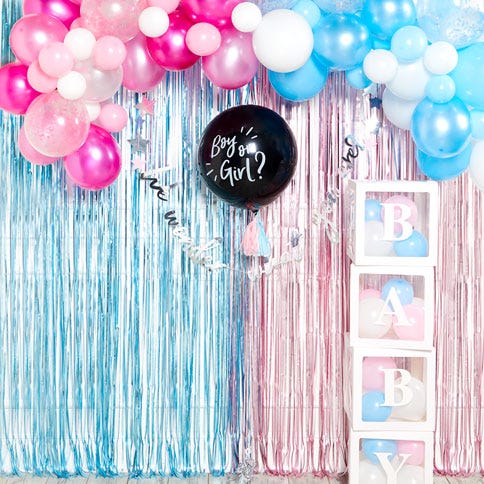 A black gender reveal balloon surrounded by pink and blue baby shower decorations